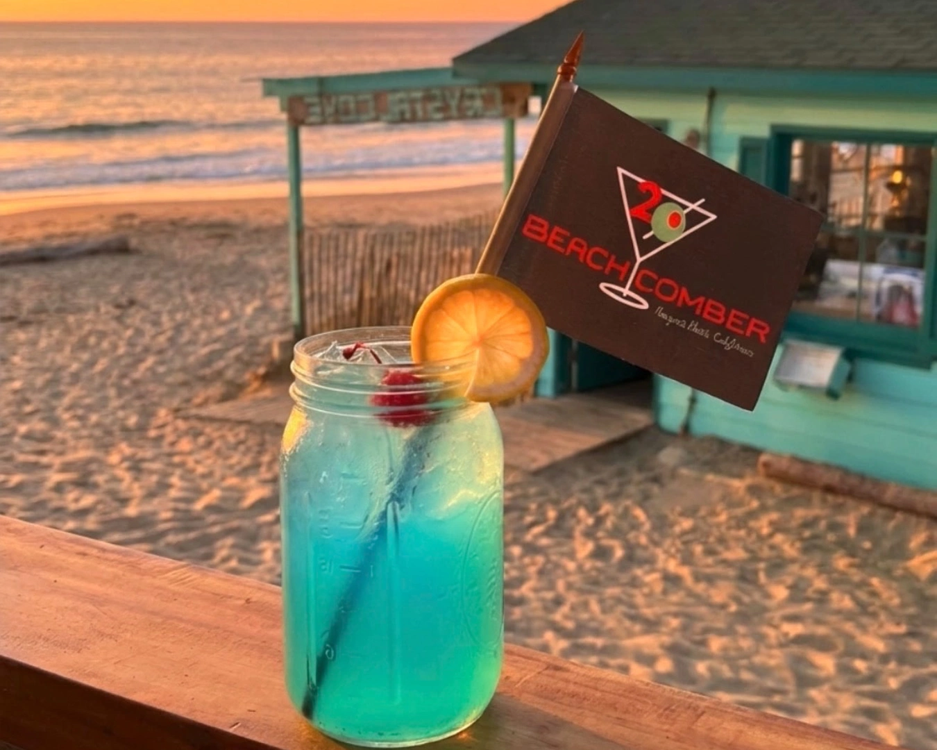 A blue cocktail in a mason jar overlooking the beach.