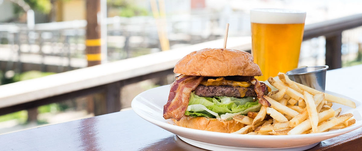 A bacon-topped burger with lettuce and French fries.